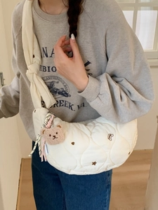 Sac bandoulière matelassé blanc avec broderie cœur et charm ours porté par le modèle