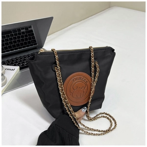 Detail of black nylon crossbody bag with cute dog patch and metal chain strap