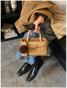 Detail view of khaki bucket bag with luxury woven texture and brown pompom charm