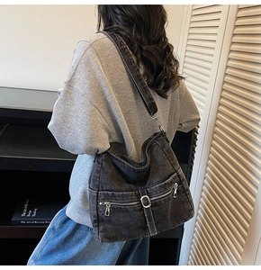 Detailed close-up of a washed denim shoulder bag with vintage metal rings and pockets