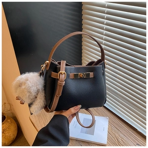 Detail of black pebbled leather bucket bag with brown handle and plush bunny charm