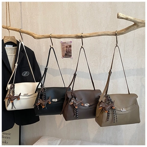 Detail of four vintage tote bags in various colors hanging on a wooden branch decor