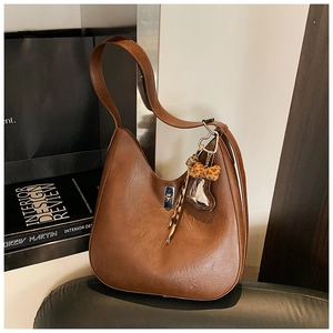 Detail of brown litchi pattern leather vintage bucket bag with leopard and heart charms