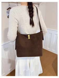 Detail of dark brown suede hobo bag featuring gold twist-lock and adjustable buckle