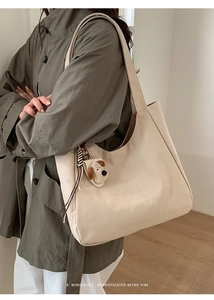Detail of beige canvas tote with dark brown strap and cute plush puppy charm