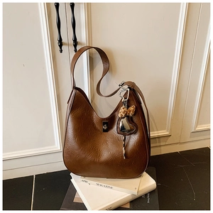 Detail of brown leather bucket bag with metallic buckle and leopard heart charm