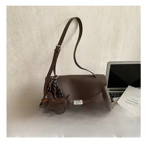 Detail of dark brown lychee leather handbag with metal lock and dog charm