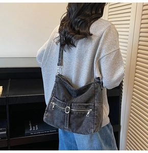Detail of vintage washed denim hobo bag featuring multiple zippers and adjustable strap