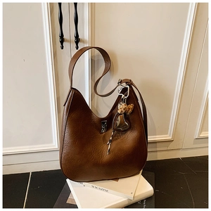 Detail of vintage brown leather bag with metallic clasp and leopard heart charm