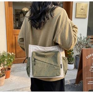 Outdoor lifestyle shot of a woman wearing a casual olive and beige contrast canvas bag