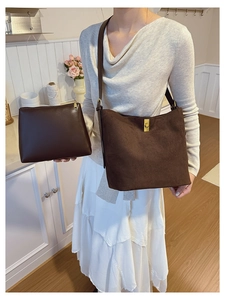 Close-up of brown suede bucket bag and matching leather pouch in warm home setting
