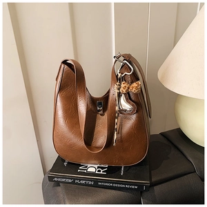 Detailed view of brown faux leather saddle bag with silver clasp and leopard bow charm