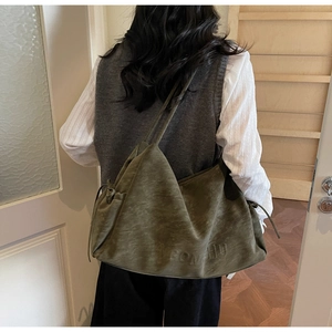 Detail of olive green tote bag featuring embossed logo and drawstring side accents