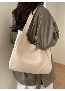 Detail of a beige canvas tote bag with C'est la vie embroidery for casual daily use