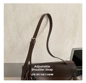 Detail of adjustable shoulder strap with silver buckle on brown lychee leather briefcase