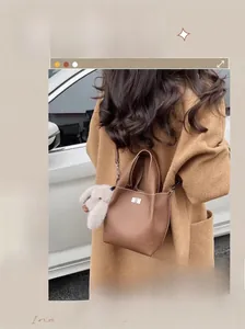 Close-up of brown pebbled leather bucket bag with silver lock and plush rabbit charm
