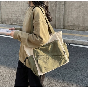 Detail of color-block tote bag with front zipper pocket and adjustable drawstring