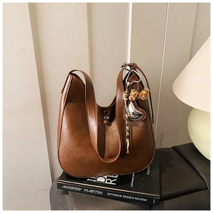 Detail view of vintage brown leather hobo bag with leopard bow and metal heart charm