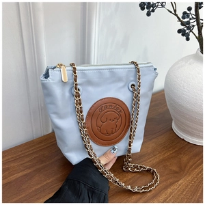 Detail of light blue fabric bag with vintage chain strap and cute dog logo patch