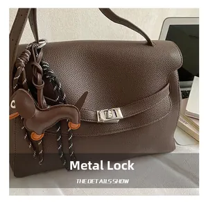Detail of silver twist lock on dark brown pebble leather tote bag with dog charm