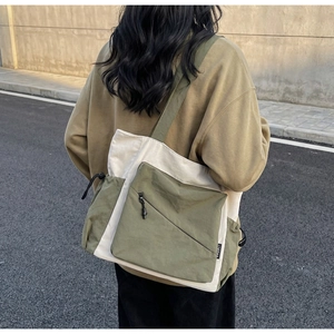 Detail of cream and olive green tote bag featuring diagonal zipper and drawstring pocket