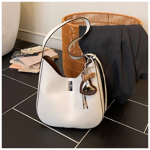 Detail of cream pleated shoulder bag featuring a silver lock and leopard heart charm
