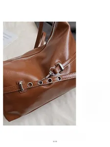 Détail macro du sac en cuir huilé caramel brillant avec fermeture éclair en métal argenté