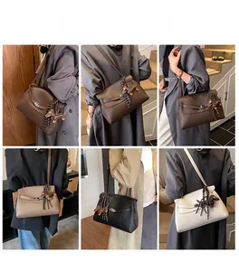 Litchi pattern leather trapezoid handbag with scarf detail shown on models in daily life