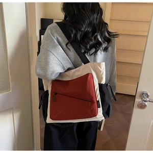 Detail of color-block tote bag featuring side drawstrings and smooth metal zippers