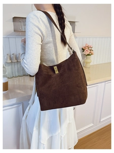 Detail of dark brown suede bucket bag featuring a vintage gold twist lock buckle
