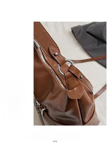 Détails d'un sac en similicuir marron brillant avec anneaux métalliques et rivets argentés