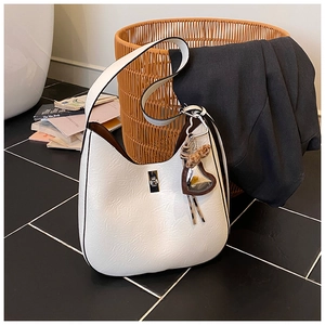 Detail of white leather hobo bag with heart pendant and silver turn-lock buckle