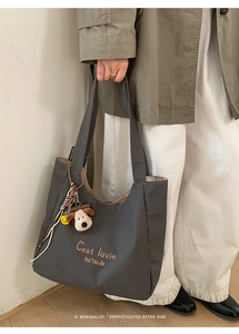 Detail of dark grey canvas tote bag with shoulder strap and cute plush dog charm