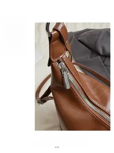 Vue détaillée de la fermeture éclair argentée sur le sac à bandoulière en cuir brun