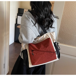 Detail of color-block tote bag featuring red and beige canvas with a zip pocket