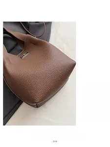 Detailed macro view of brown lychee grain leather bucket bag with silver metal lock