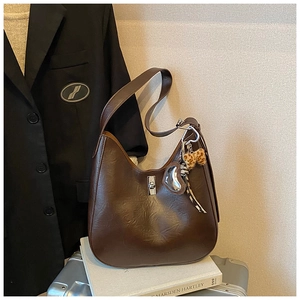 Detail view of retro brown PU leather shoulder bag with silver clasp and leopard charm