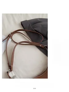 Détail de la bandoulière en cuir marron avec boucle réglable et rivets métalliques