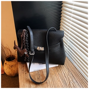 Detail of black lychee grain leather handbag with silver lock and puppy charm