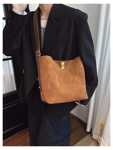 Detail of vintage brown suede bucket bag featuring elegant gold metal twist lock