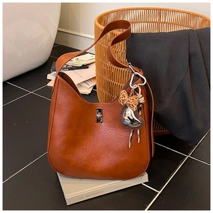 Detail of caramel leather shoulder bag with leopard bow and silver heart charm