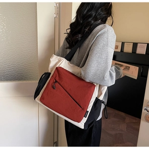 Detail of color-block tote bag featuring side drawstrings and front zipper pocket detail