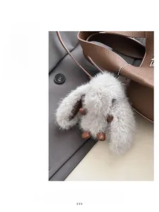 Detailed view of a plush rabbit charm with grey faux fur on a brown leather bucket bag