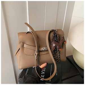 Detail of khaki brown litchi leather tote bag with elegant flap lock and dog charm