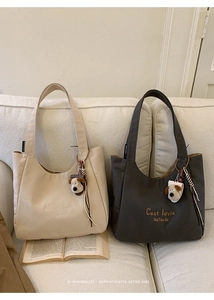 Detail of minimalist canvas tote bags with C'est la vie embroidery and dog charms
