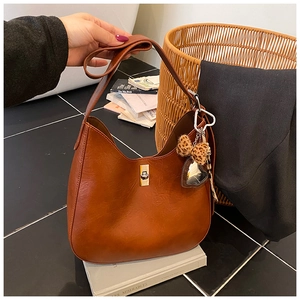 Detail view of caramel brown hobo bag with gold metal buckle and heart leopard pendant