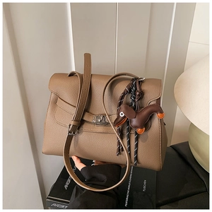 Macro detail of brown litchi grain leather tote with metal buckle and dog charm