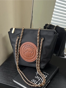 Retro black nylon shoulder bag with chain strap and cartoon dog emblem on desk