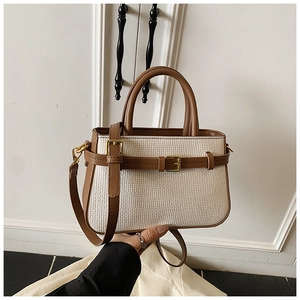 Close-up of beige woven crossbody bucket bag with brown leather trim and gold hardware