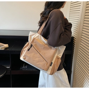 Side view of beige and brown canvas tote bag with multi-pocket design and drawstring detail